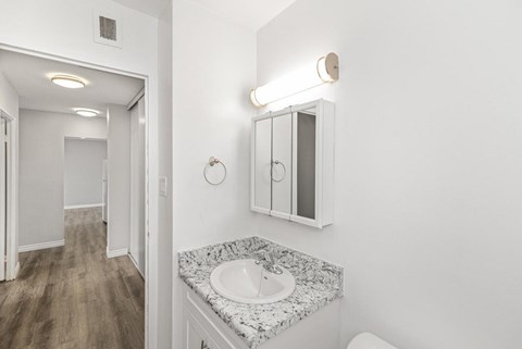 A bathroom with a marble countertop and a white sink.