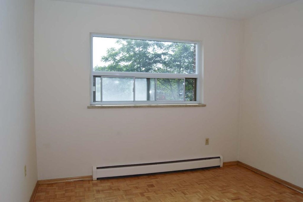 A room with a window and a radiator on the floor.