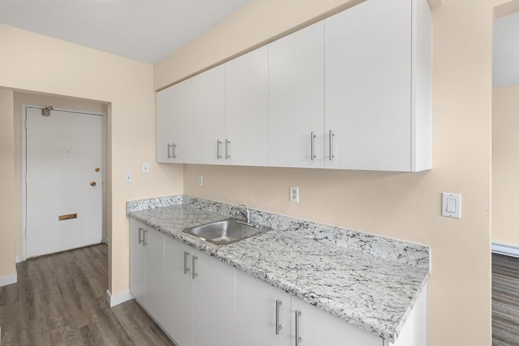 A kitchen with white cabinets and a marble countertop.
