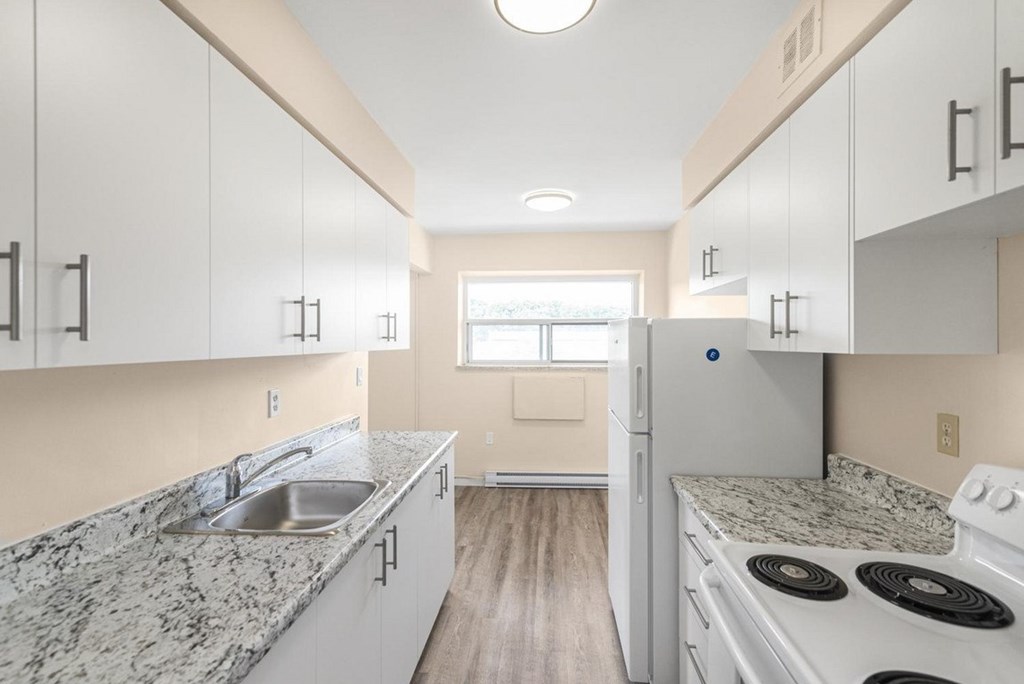 A kitchen with white cabinets and a granite countertop.