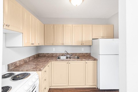 A kitchen with a white refrigerator and a white stove with a marble counter top.