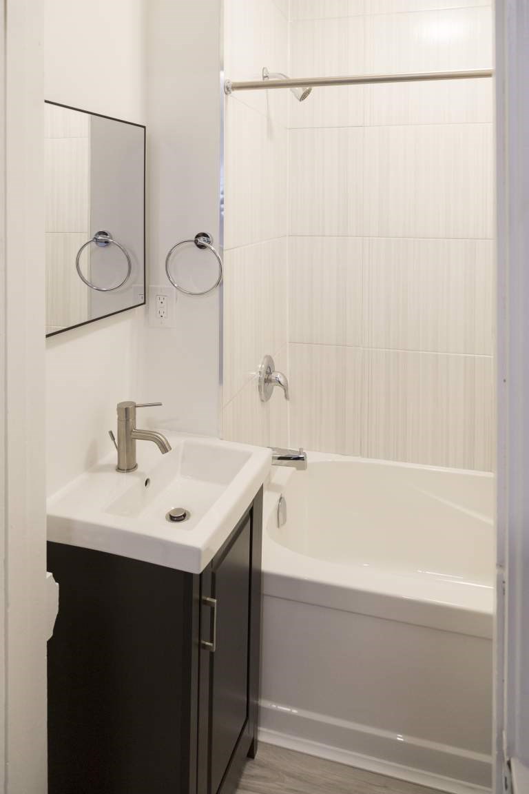 A white sink with a silver faucet is on a black countertop.