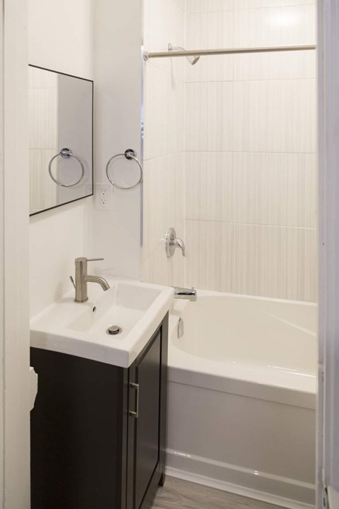 A white sink with a silver faucet is on a black countertop.