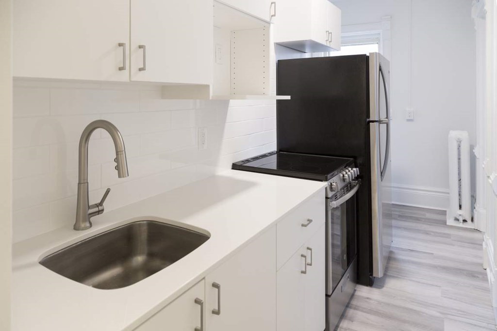 A modern kitchen with a black refrigerator and stainless steel sink.