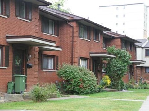 A red brick building with green bushes in front.