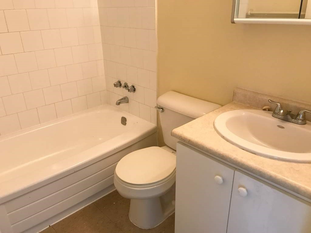 A white toilet sits next to a bathtub in a bathroom.