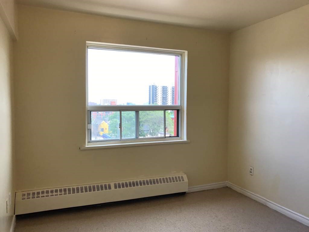 A room with a window and a radiator on the floor.