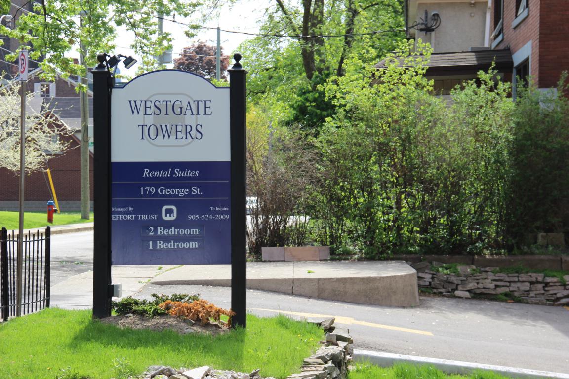 A sign for Westgate Towers rental suites stands in front of a building.