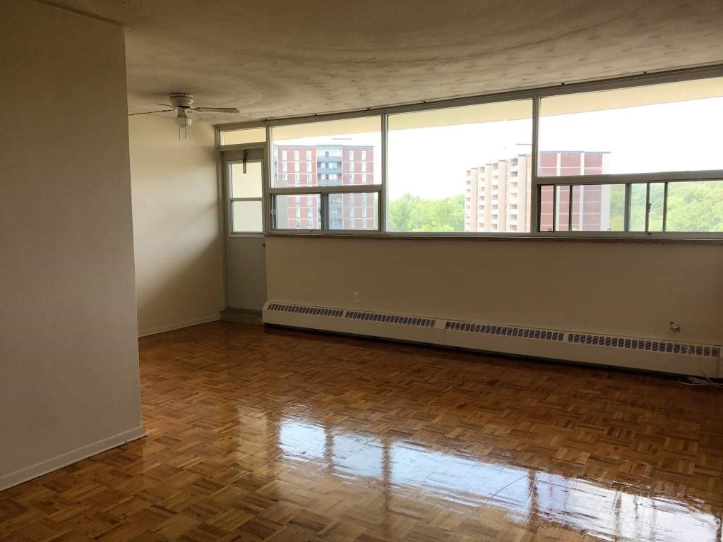 A room with wooden flooring and a window overlooking a cityscape.