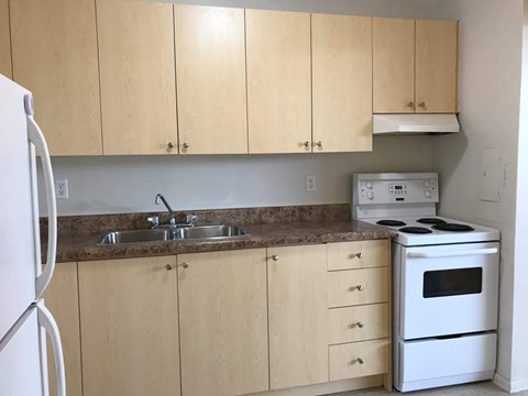 A kitchen with wooden cabinets and a white stove.