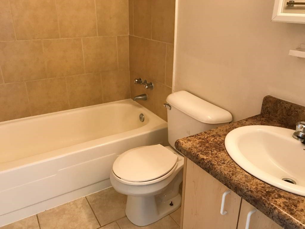 A white toilet sits next to a bathtub in a bathroom.