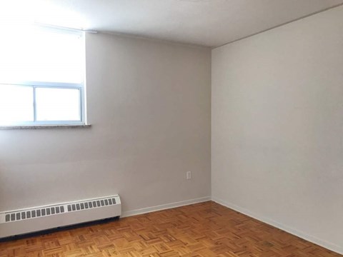 A room with a window and a radiator on the floor.