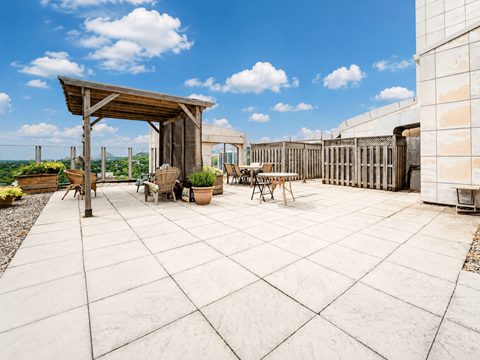 A patio with a wooden pergola and a table surrounded by potted plants.