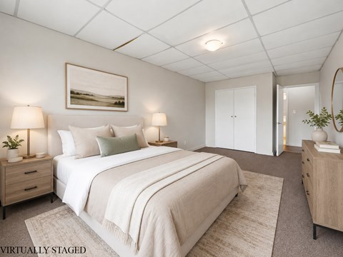A bedroom with a large bed, two nightstands, and a painting on the wall.