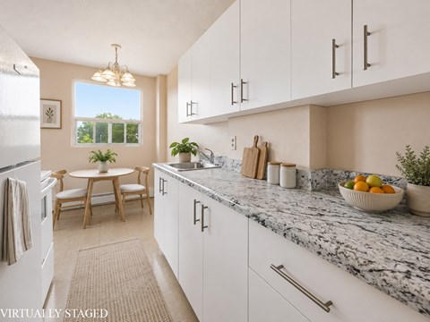 A kitchen with white cabinets and a marble countertop.