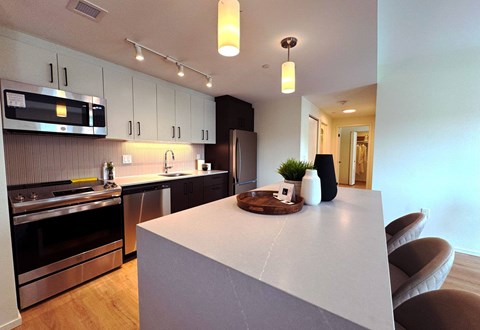 A modern kitchen with a white countertop and stainless steel appliances.