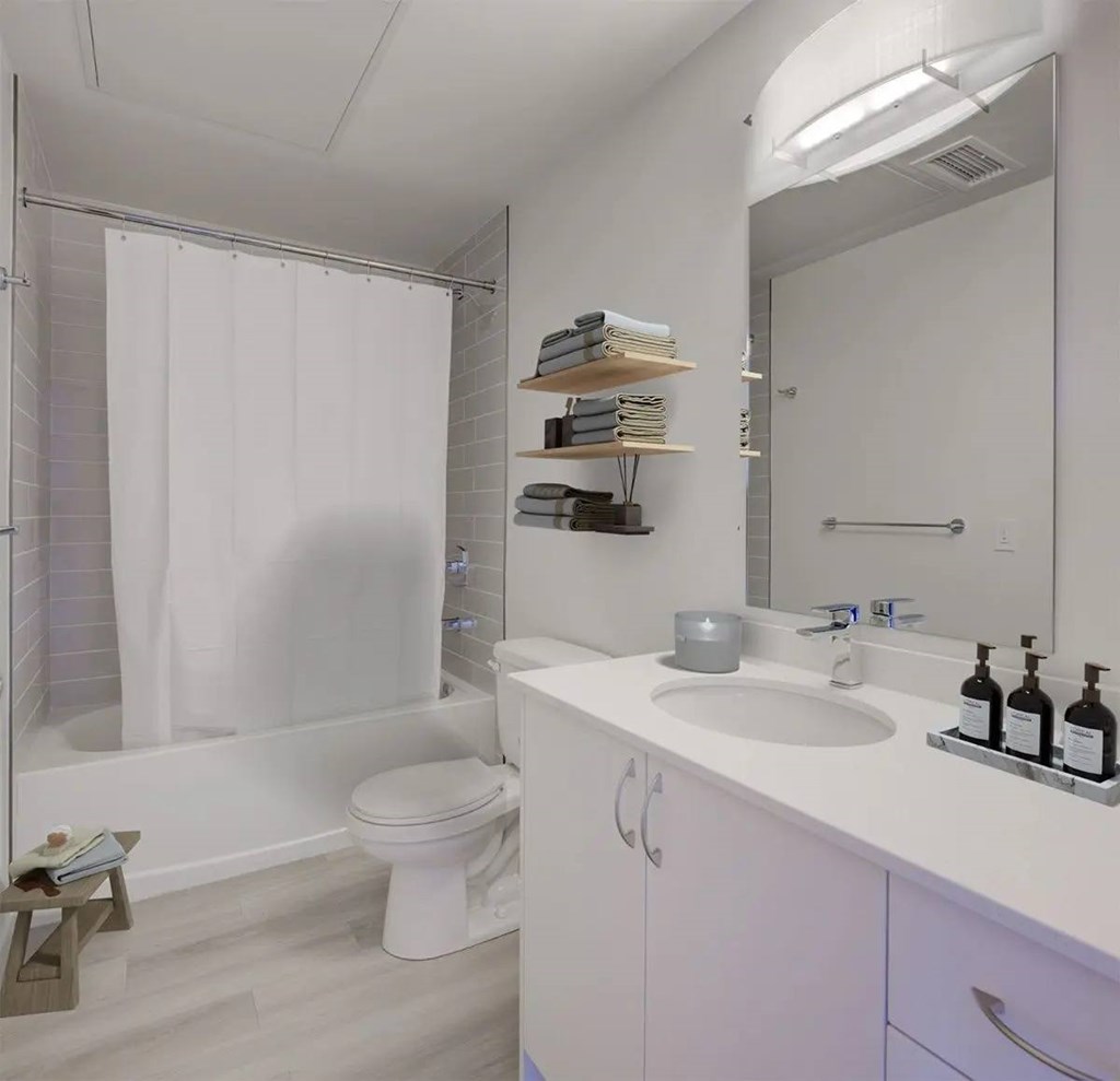 A white bathroom with a toilet, sink, and shower.at Sylk Towers, Kitchener
