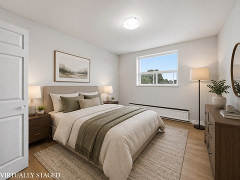 A bedroom with a large bed and a window overlooking a tree-lined landscape.