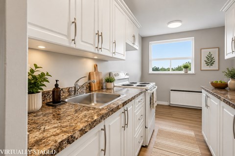 A kitchen with white cabinets and a marble countertop.