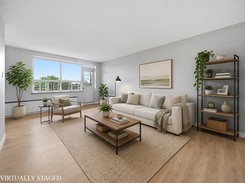A living room with a white couch, a coffee table, and a large window.