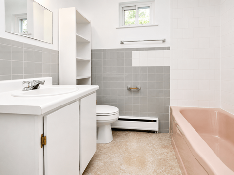 A white bathroom with a pink tub and grey tiles.