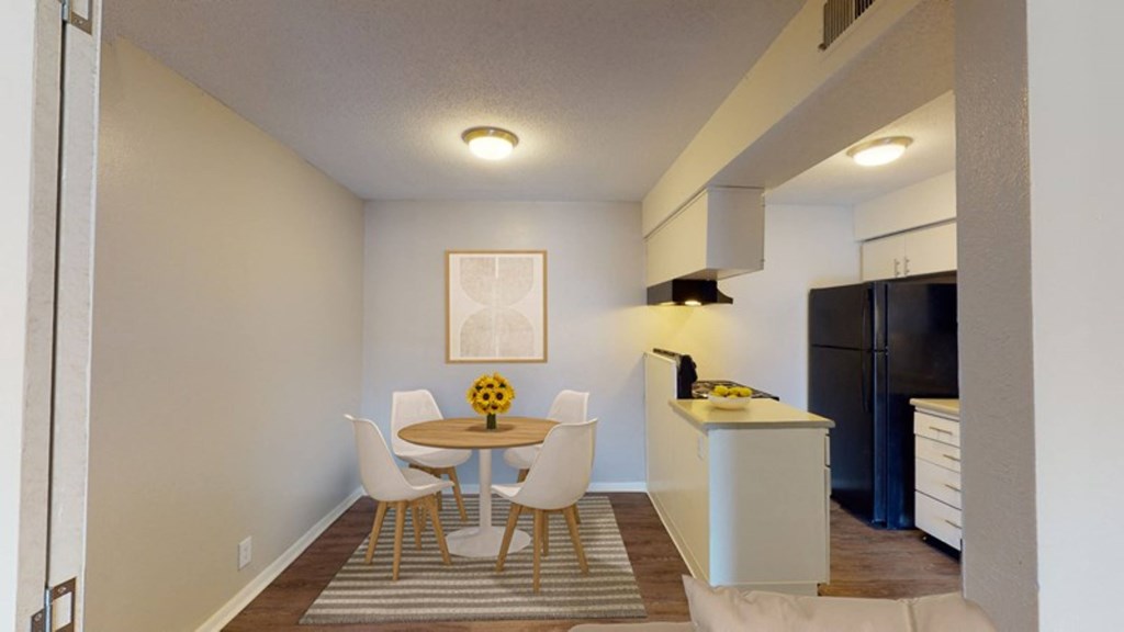 A kitchen with a refrigerator and a dining area.
