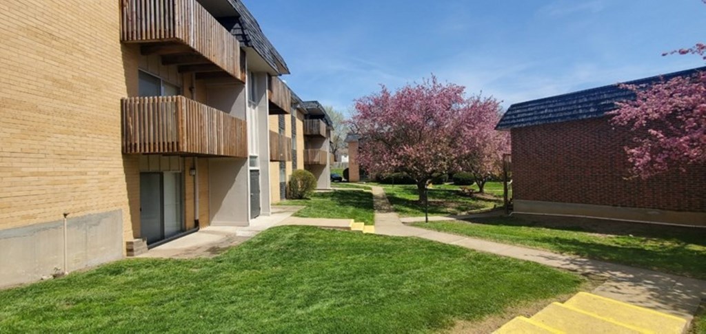 Apartment building with a green lawn and trees.