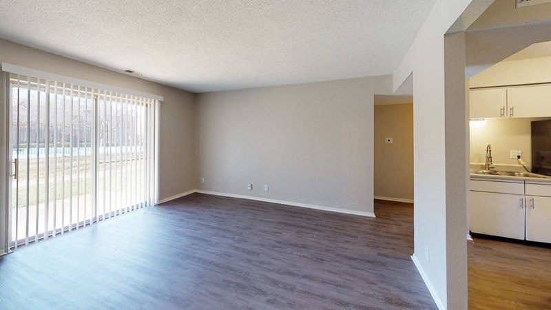 A spacious living room with a sliding glass door leading to a patio.