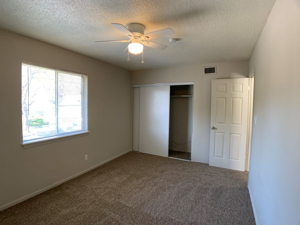A room with a ceiling fan and carpeted floor.