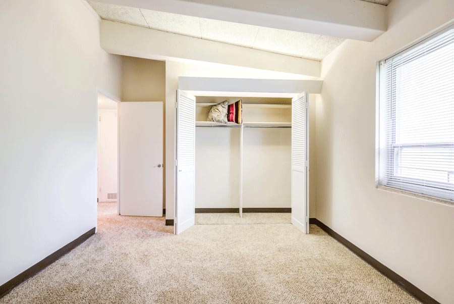 A room with a white door and a window with blinds.
