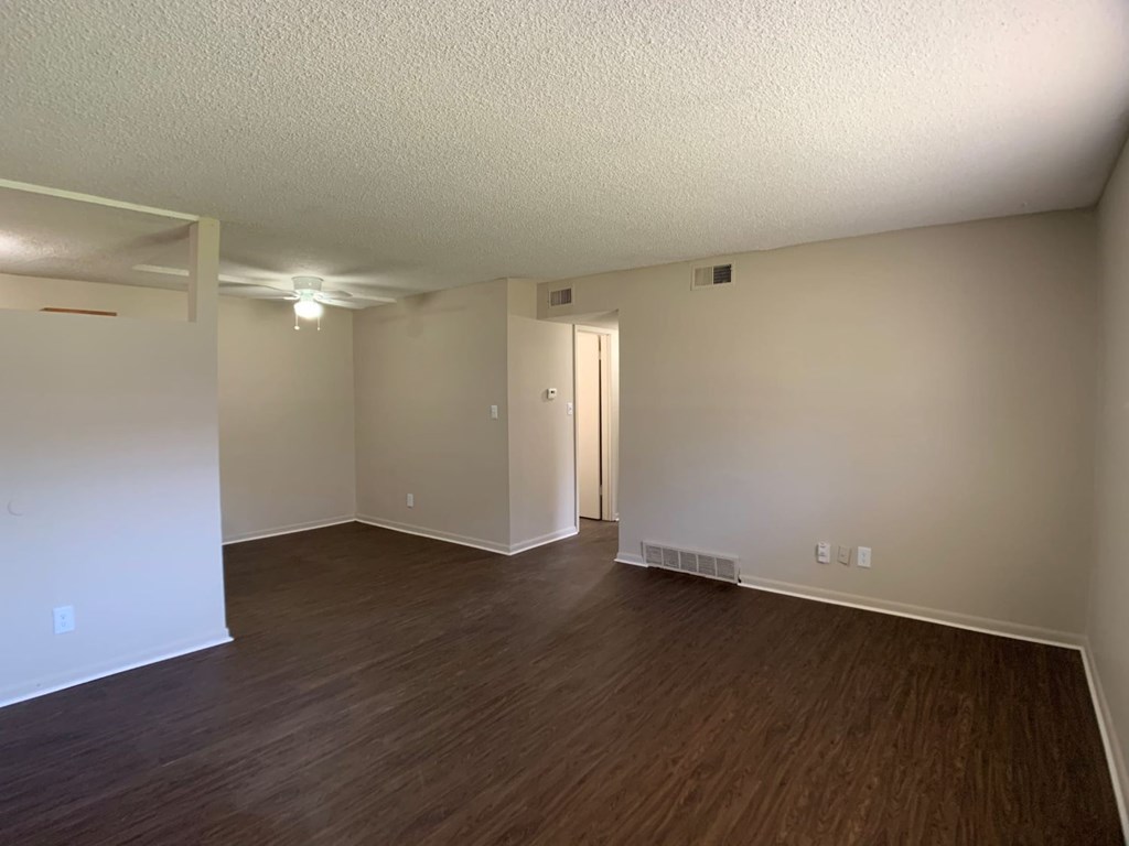 A room with wooden flooring and a door in the middle.