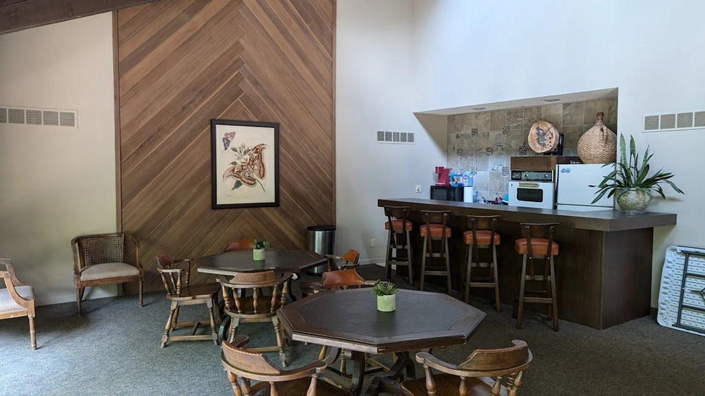 A dining room with a wooden table and chairs and a bar area.