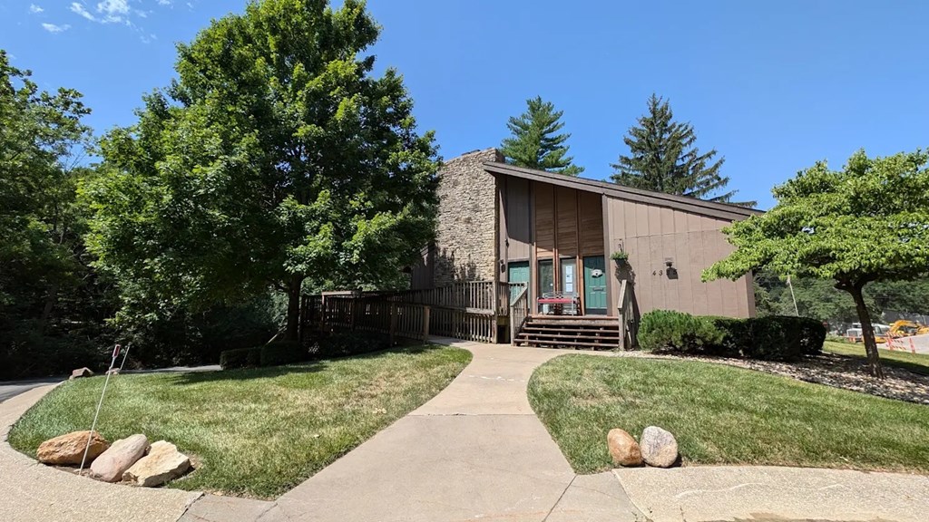 A clubhouse building surrounded by trees with a lawn in front.