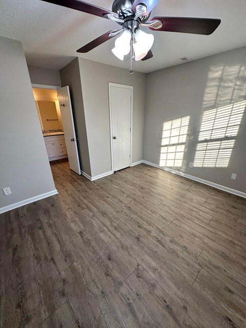 A room with a ceiling fan and wooden flooring.