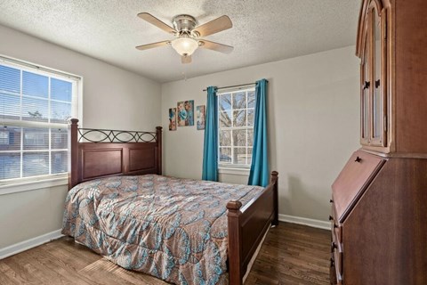 A bedroom with a bed, dresser, and window.