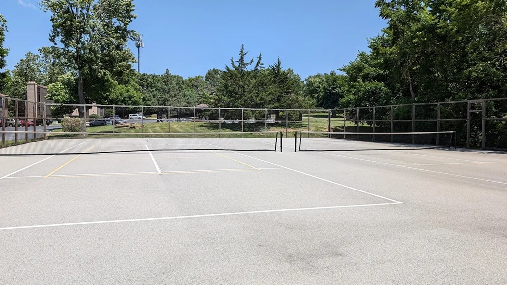 A tennis court surrounded by a fence and trees.