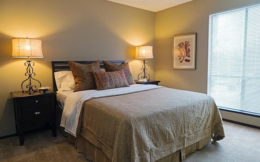 A bedroom with a bed, two nightstands, and two lamps.