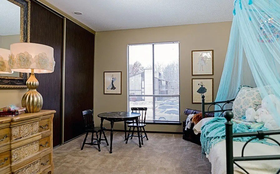 A bedroom with a bed, a dresser, a table, and chairs.