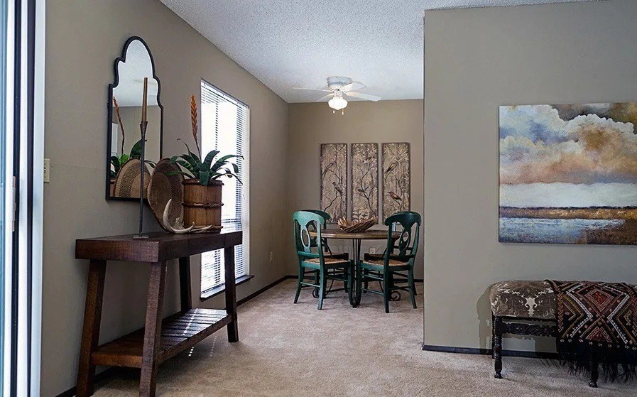 A room with a mirror, a table and chairs, a bench, and a painting on the wall.