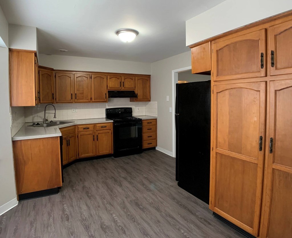 A kitchen with wooden cabinets and black appliances.