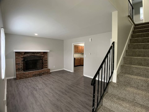 A living room with a fireplace and a staircase.