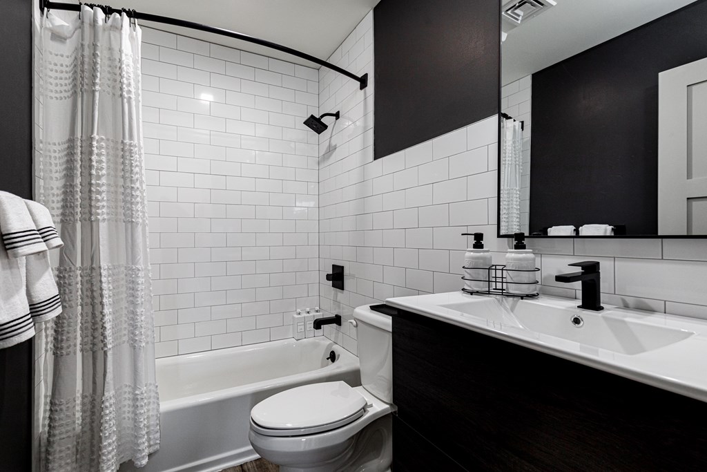 A white toilet sits next to a white bathtub in a black and white bathroom.