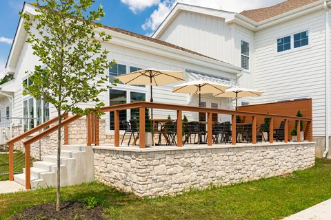 A white house with a stone wall and a tree in front.