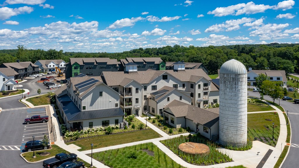 A large white silo stands in front of a row of houses.