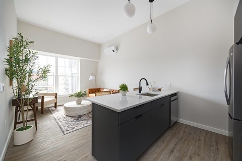 A kitchen with a grey island and a refrigerator on the right.