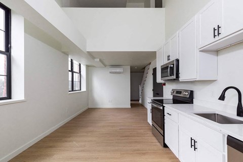 A kitchen with white cabinets and a wooden floor.