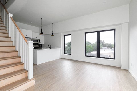 A spacious living room with a staircase on the left side.