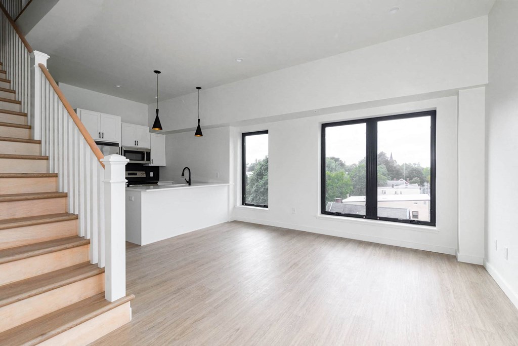 A spacious living room with a staircase on the left side.