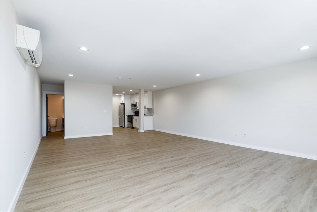 A spacious room with wooden flooring and white walls.