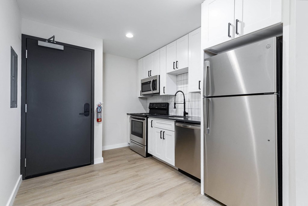 A modern kitchen with a black door and stainless steel appliances.